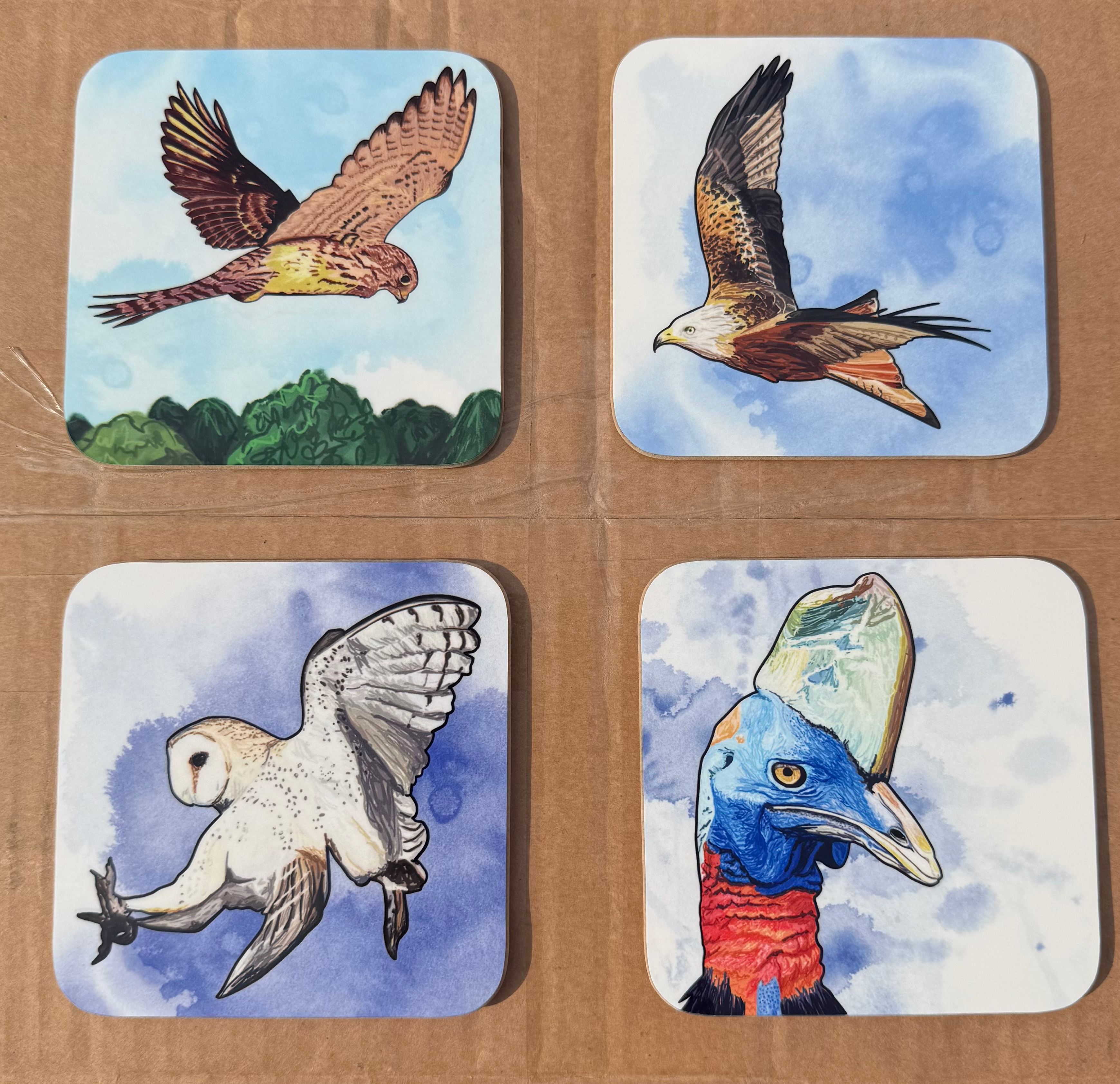 four bird themed coaster samples. Clockwise from top left they show a kestrel hovering over some trees, a red kite flying, the head and neck of a Cassowary and a swooping barn owl.