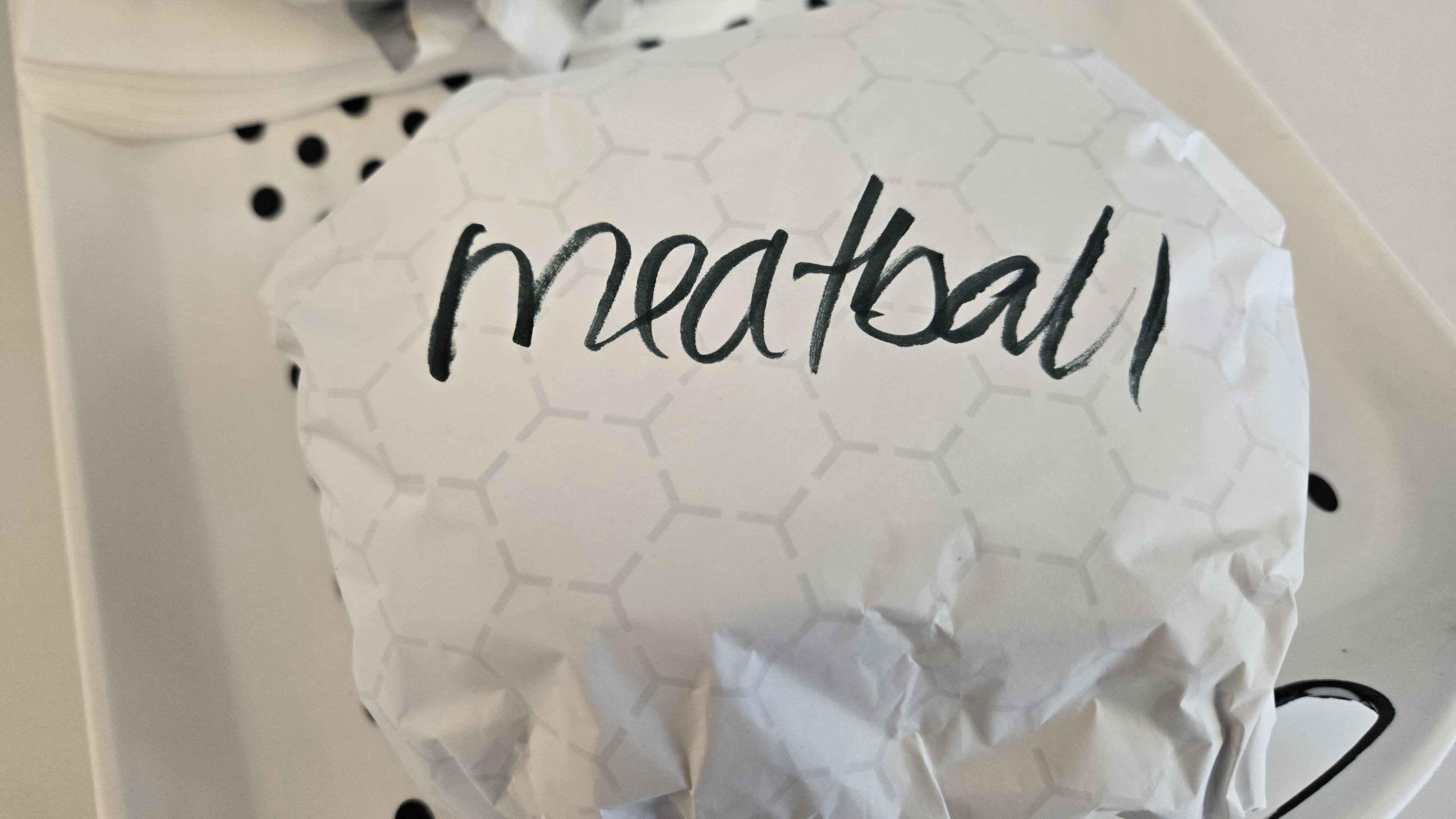  Photo of a large wrapped object that has MEATBALL written on the top in sharpie