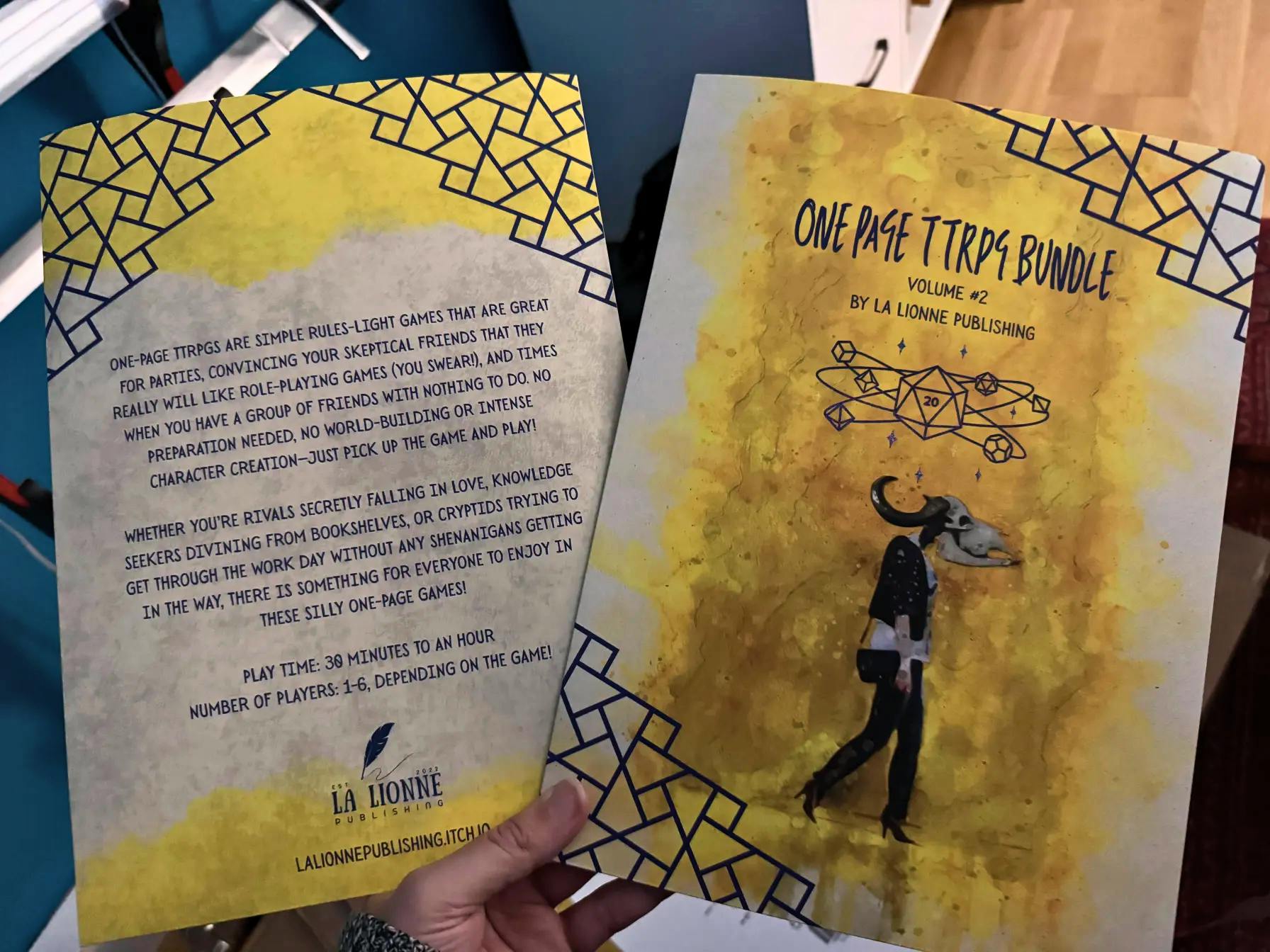 Two yellow and parchment-colored folders, front and back, held up in the air by one hand. The folders feature the project's business woman cryptid and space d20 artwork on the front and the project's description on the back.