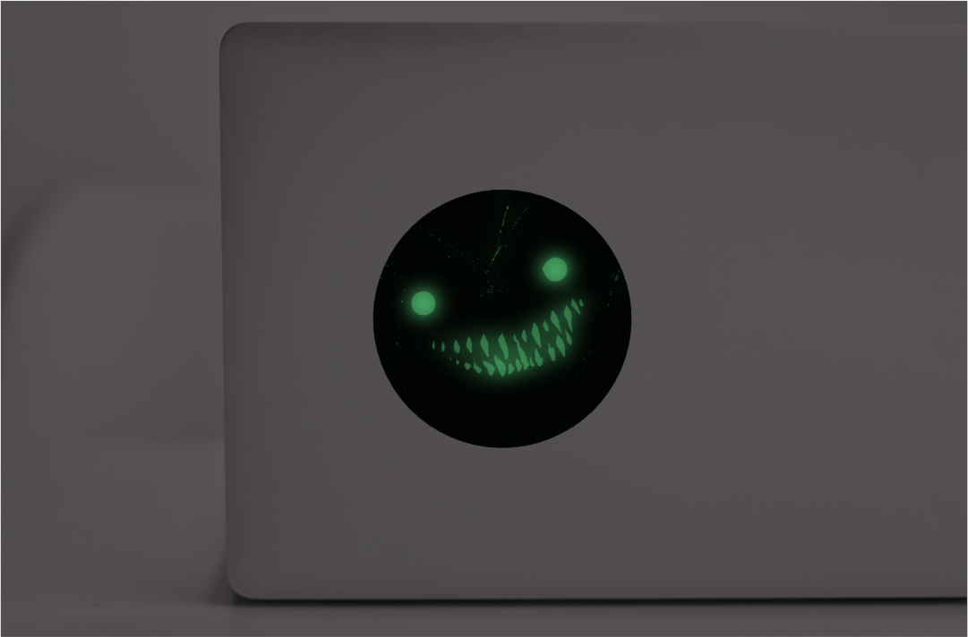Digital mockup showing a laptop with a glow in the dark sticker of the eyes and teeth monster art by Kim Holm featured on the cover of the Alone in the Dark solo tools pamphlet.