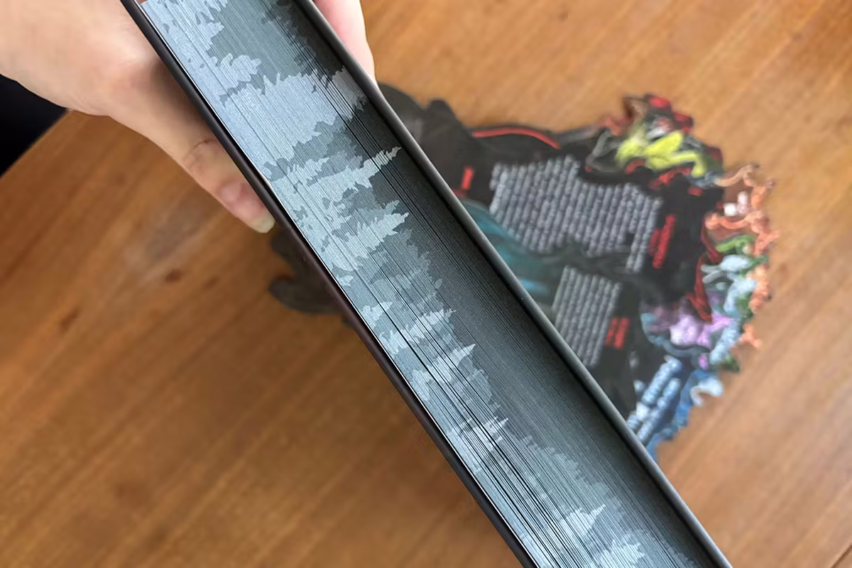 Photo of the deluxe edition of The Darkest Woods edge-on, showing the page-edge printing and the hefty thickness of the book.