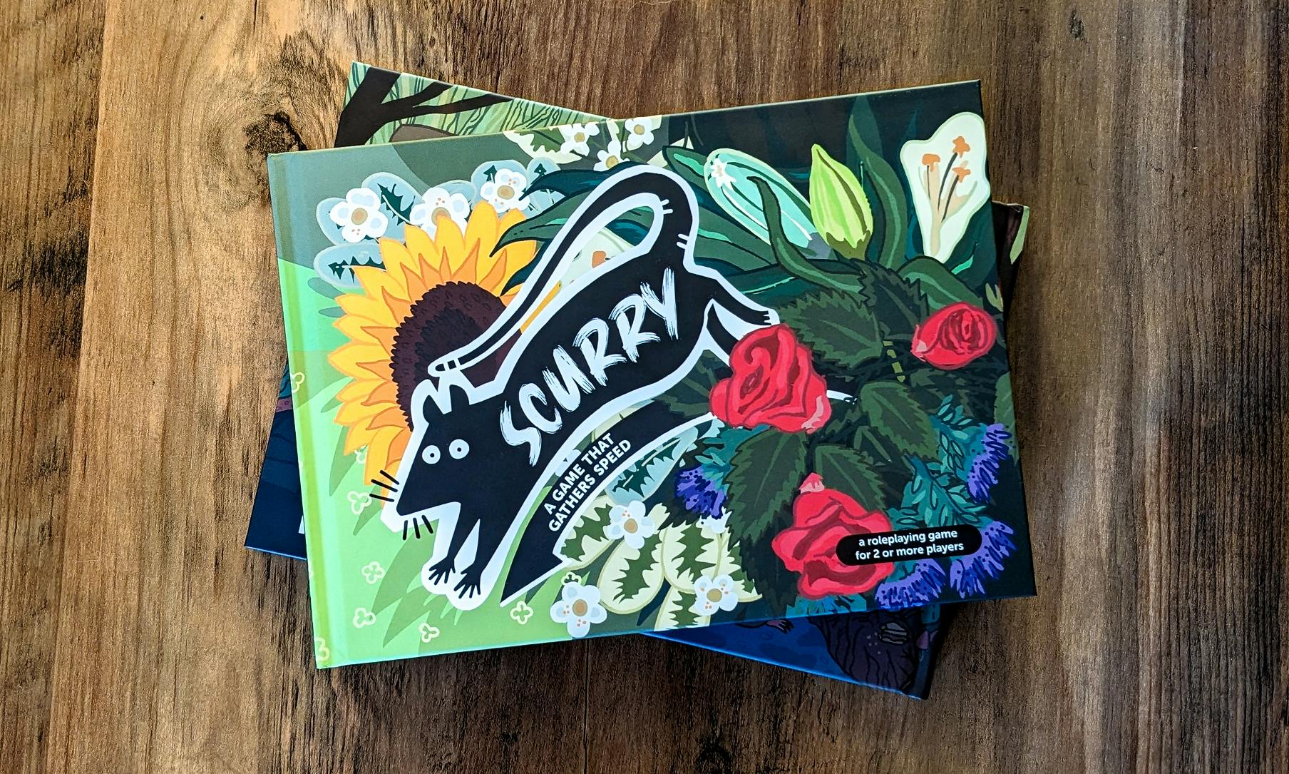 A product photo of two Scurry hard cover books against a wooden table. The cover illustration shows a black cartoon rat leaping out of a bundle of flowers and herbs.The