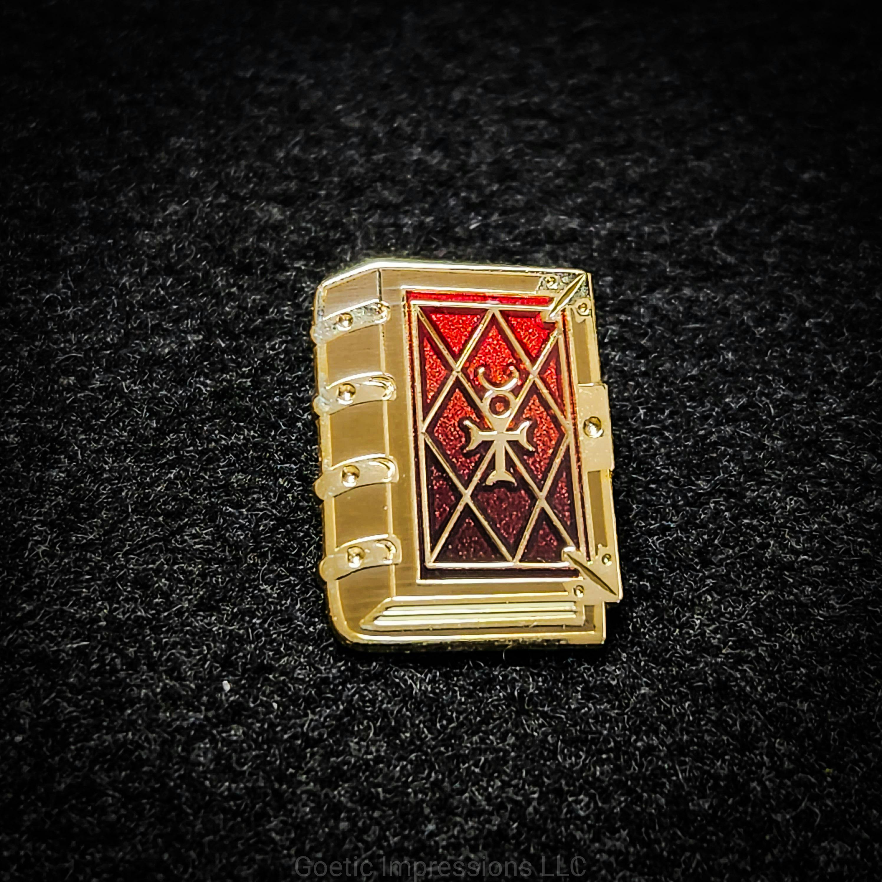 Gold plated enamel pin featuring a grimoire with the mercury sigil on it