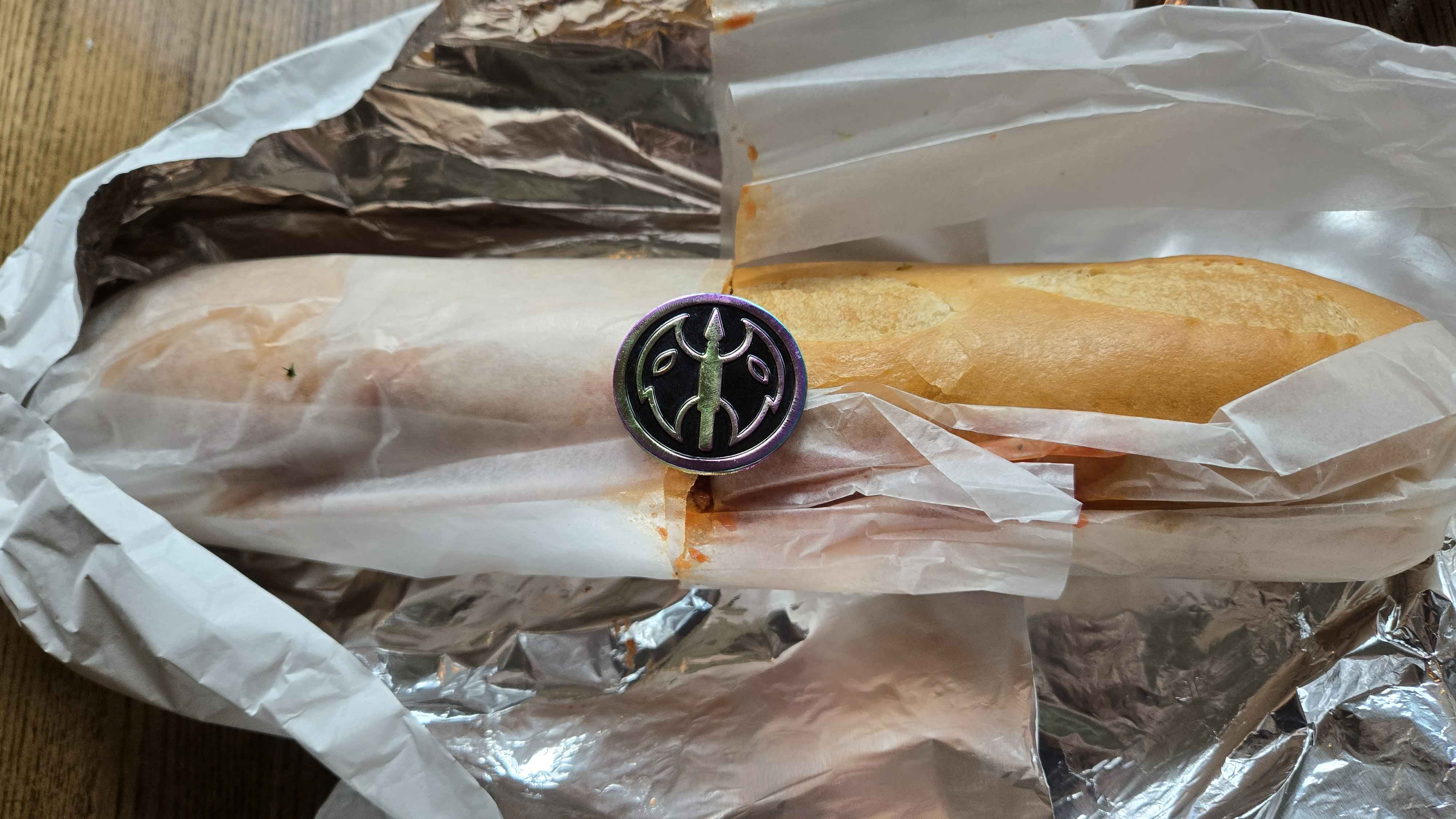  A foot long meatball sub with a battle-axe rainbow metal pin resting on the middle. 