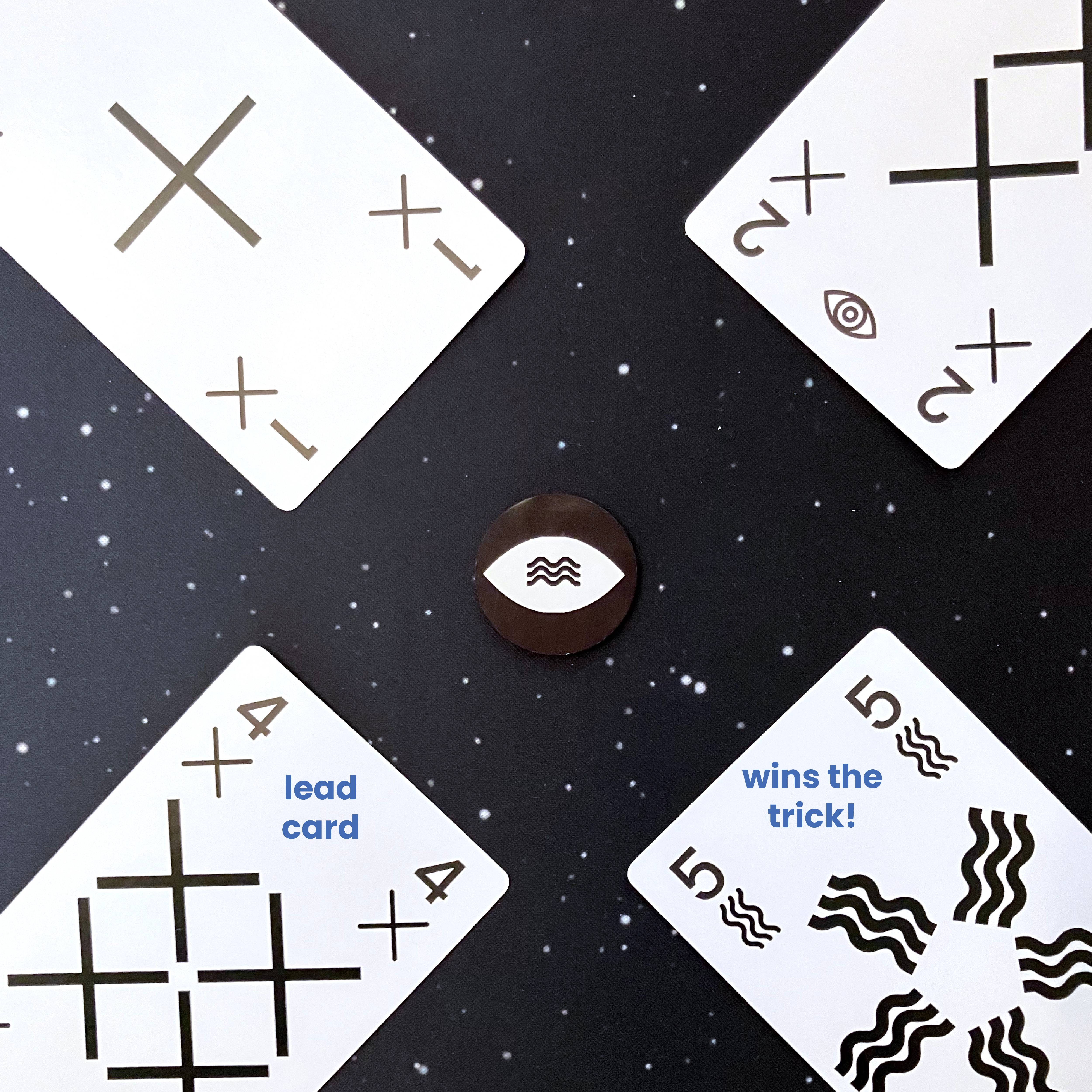 4 of Crosses leads, but 5 of Squiggles wins the trick because Squiggles are Supernatural.