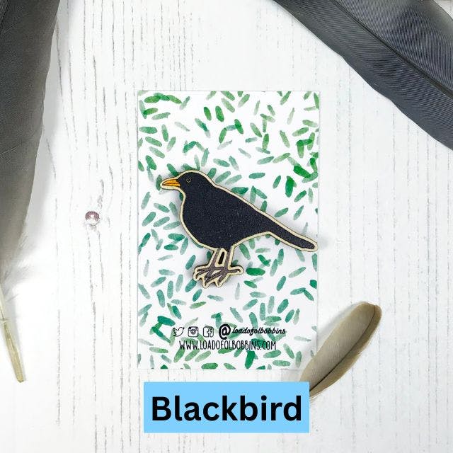a wooden pin created from an illustration by Loadofolbobbins of a male blackbirdhttps://www.backerkit.com/c/projects/loadofolbobbins/loadofolbobbins-holiday-shop